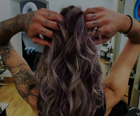 cheveux longs bouclés avec des mêches violettes et des tatouages sur les mains